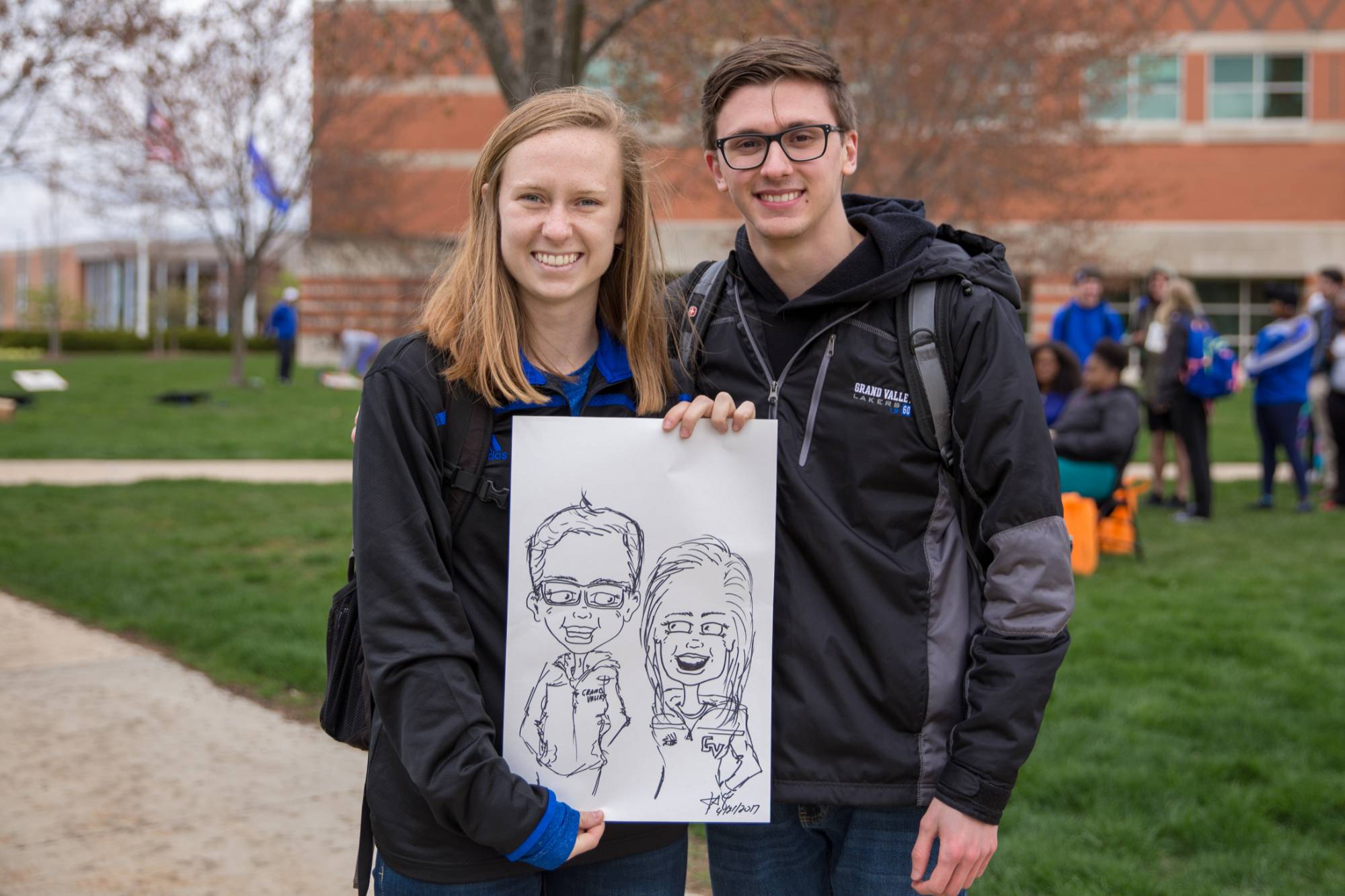 2 GVSU students holding caricatures of themselves at ExtravaGRANDza